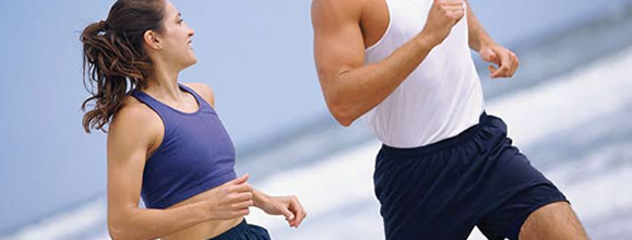 Pareja corriendo a la orilla de la playa